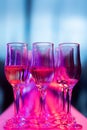 Still life image of a pair of wine glasses sitting atop a pink cloth on a table