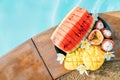 Still life image of tropical fruits and flowers near the pool: water melon, mango, mangosteen, passion fruit