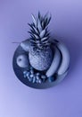 Still-life image of various fruits and a pineapple on a plate, with blue hues