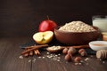 Still life of ingredients for healthy diet: oat flakes in bowl with apple, cinnamon, nuts, honey, milk on wooden table. Royalty Free Stock Photo