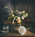 Still life with a jug, a glass, a dandelion wildflowers and a butterfly.