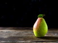 Still life of a juicy pear on old, grunge wooden table and dark background. Selective focus. Copy space. Low light.