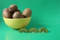 Still life kiwi fruit in a yellow bowl plate and next to a kiwi copyspace slice Royalty Free Stock Photo