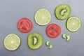 Still life of kiwi, lime and tomato fruit slices on gray Royalty Free Stock Photo
