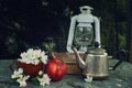 Still life with a lantern, an apple, a metal kettle and a large book on a green marble table, soon to school