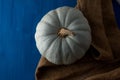 Still life of light pumpkin lies on a rough brown bag for vegetables on a blue background top view close-up