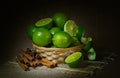 Still life, lime fruit in a wicker basket, cinnamon, dark background