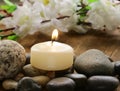 Still life a lit candle and stones Royalty Free Stock Photo