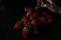 Still life in low key with bunch of fresh red grapes, fresh oranges and fresh strawberries