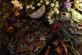 Still life with magic book of spells and beautiful flowers on witch ritual table.