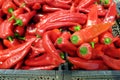 Still life with many long ripe hot red chilli peppers in the black plastic boxes in the vegetable department store shop front view Royalty Free Stock Photo