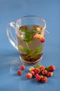 Still life of a mug of herbal tea on blue ceramic tiles with dust texture and reflection. Near scattered strawberries. Focus on th Royalty Free Stock Photo