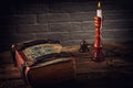 Old books, candle, pen, ink  on wooden table against brick background Royalty Free Stock Photo