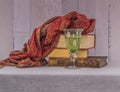 Still life with old books, a glass of drinking water and a luxurious cashmere shawl