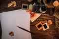 Autumn still life with an old camera, sweater, photos and fallen leaves on wooden background