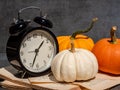 Still life with old fashion alarm clock, pumpkins and old book on dark background Royalty Free Stock Photo