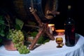 Still life with old oak wine barrel, and bronze container with bunch of grapes, and candles on black background Royalty Free Stock Photo
