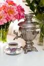 Still life with old russian samovar, rustic cup of tea, bouquet with peony flowers, glasses and candles Royalty Free Stock Photo