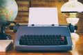 Still life of old typewriter with empty sheet, globe and old fashioned lamp