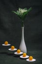 Still life with orange balls on white stands and a bouquet of lilies of the valley in a white vase Royalty Free Stock Photo