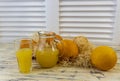 Still life with oranges, basket and glass jug with juice on old bright wooden background