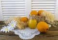 Still life with oranges, basket and glass jug with juice on old wooden background