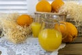 Still life with oranges, basket and glass jug with juice on old wooden background