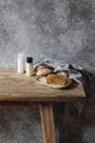 Still life of organic handmade soap bar, wooden brush, moisturizer, shamppo bottles and linen towel on wooden bench. Spa