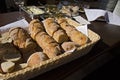 Still life with pastry and bread in wicker basket on wooden table with plates, bowls and vegetable salad Royalty Free Stock Photo