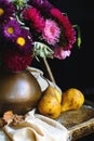 Still life with pears and a bouquet of flowers in a copper jug on a wooden table.. Royalty Free Stock Photo