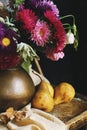 Still life with pears and a bouquet of flowers in a copper jug on a wooden table.. Royalty Free Stock Photo