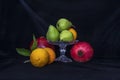 Still life. Pears in a glass vase, oranges and pomegranates on a black background Royalty Free Stock Photo