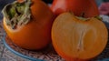 Still life with persimmon on a plate on a dark background.