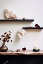 Still life photography of dried flowers, a candle, and decorative objects on wooden shelves against a white wall in a minimalist Royalty Free Stock Photo