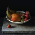 Still life photography of fresh fruits in a white plate on black background Royalty Free Stock Photo