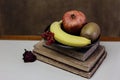 a still life with a pile of old books, fruit on a plate Royalty Free Stock Photo
