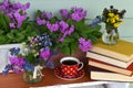 Still life with primula and pansy viola flowers, cup of tea and pile of poem books outside in porch