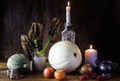 Still life with pumpkin, dead pumpkin leaves, candles, earthenware vase and old silver