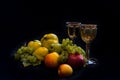 a still life with quinces, grapes, pears and apples with two glasses of wine and black background Royalty Free Stock Photo