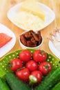 Still life of raw food in white plates on a wooden table. Frozen salmon on a plate next to cucumbers and tomatoes grated