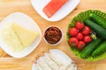 Still life of raw food in white plates on a wooden table. Frozen salmon on a plate next to cucumbers and tomatoes grated