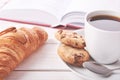 Still life with red book, cup of coffee or tea and two cookies. Croissant on white table top Royalty Free Stock Photo