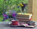 Still life with red cup of tea, books and bunch of spring flowers