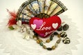 Still life with a red heart and an inscription Love you, beads, a fan, chocolates, flowers on an openwork white napkin