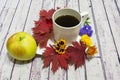 Still-life. red leaves, yellow and blue flowers. white Cup on light wood background Royalty Free Stock Photo