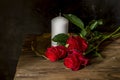 Still life with red roses and white candle close-up