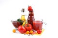 Still life of red and yellow tomatoes, bottle of tomato sauce and olive oil on white background.