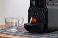 Still life of refreshing espresso capsule and cup next to coffee machine indoor at home. Nobody