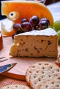 Still life Roquefort cheese, red and green grapes, crackers on wooden plate Royalty Free Stock Photo