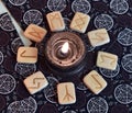 Still life with runes around burning black candle on tarot cards